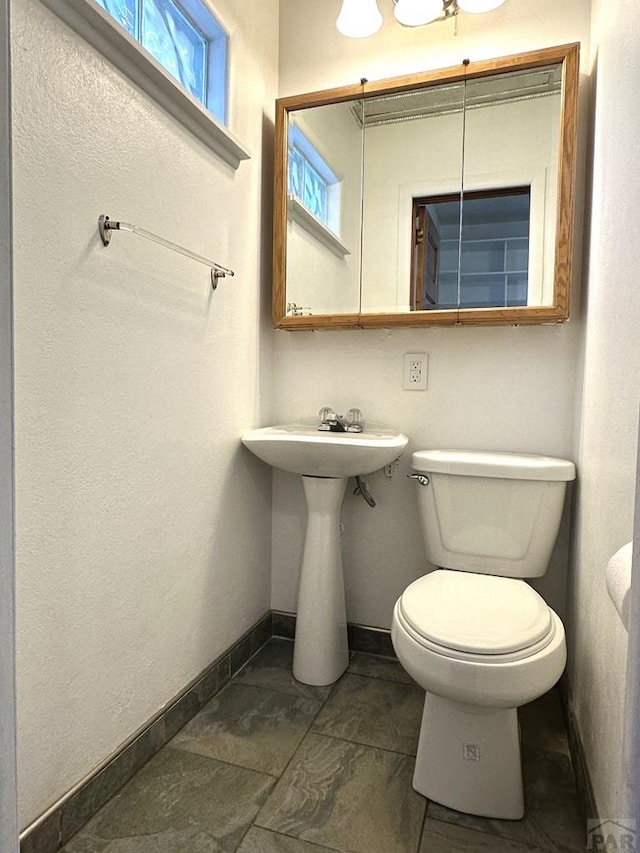 half bath featuring toilet and baseboards