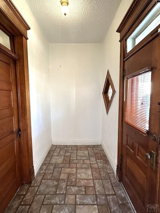 interior space featuring brick floor, baseboards, and a textured ceiling