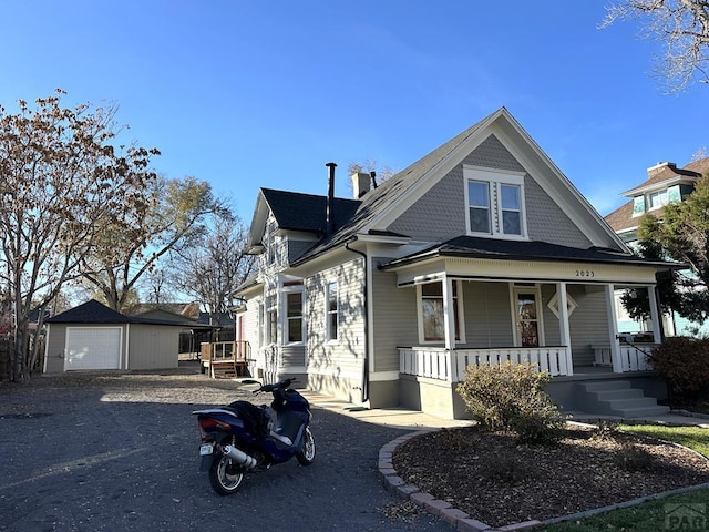 view of front of home featuring a garage, covered porch, and an outdoor structure