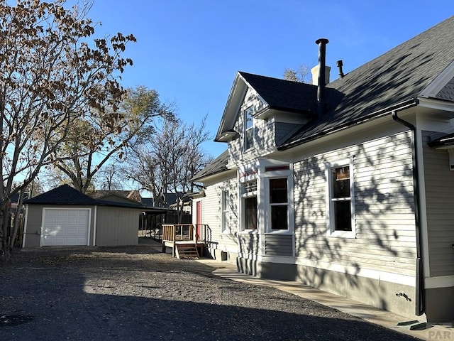 2023 N Elizabeth St, Pueblo, CO 81003 - view of home's exterior with an outdoor structure, a wooden deck, dirt driveway, a detached garage, and a shingled roof