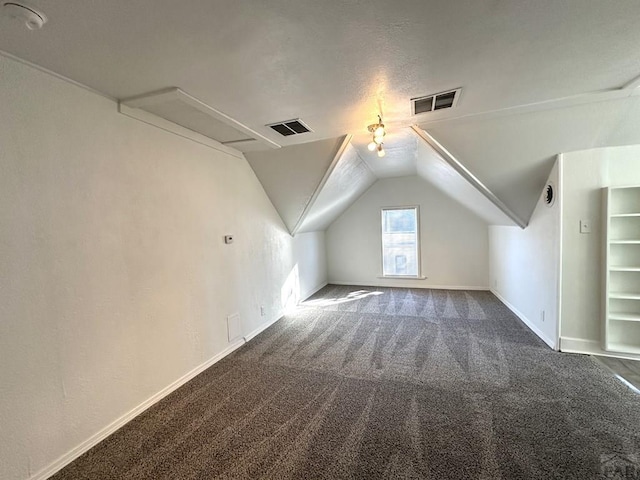 additional living space with lofted ceiling, dark carpet, visible vents, and baseboards