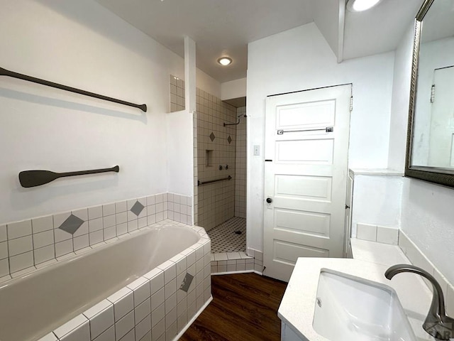 bathroom featuring a garden tub, a shower stall, vanity, and wood finished floors