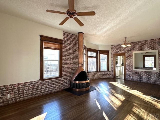 unfurnished living room featuring dark wood-style floors, brick wall, a textured ceiling, and ceiling fan