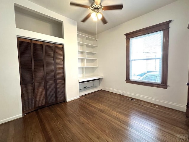 unfurnished bedroom featuring baseboards, visible vents, ceiling fan, dark wood-type flooring, and a closet