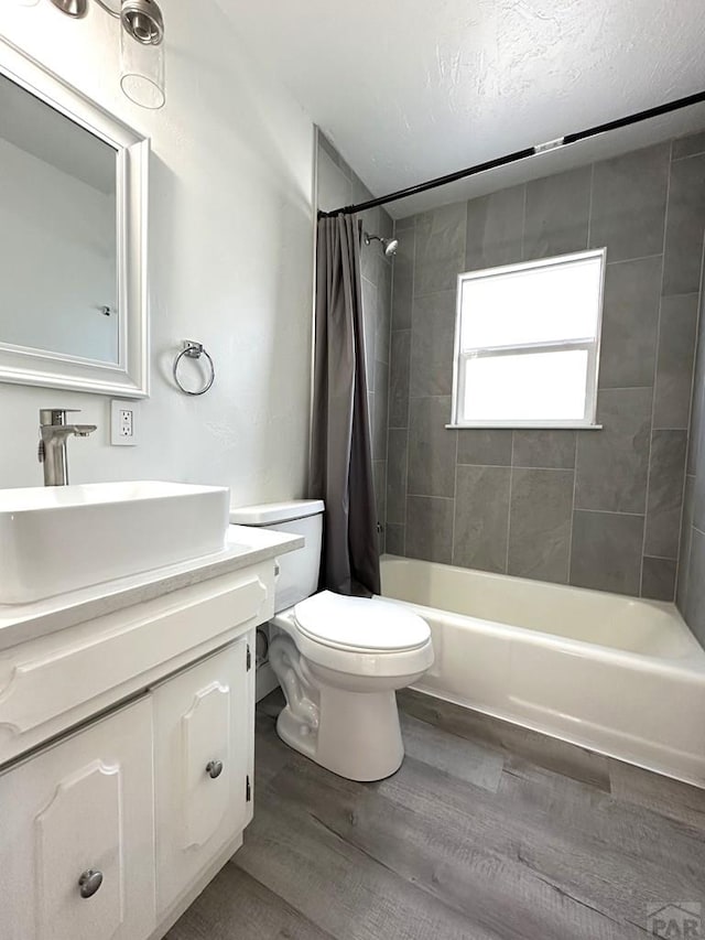 bathroom with toilet, shower / bath combo, a textured ceiling, vanity, and wood finished floors