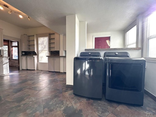 laundry room with laundry area, baseboards, a textured ceiling, and washing machine and clothes dryer