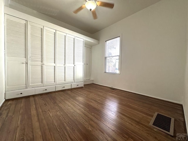 unfurnished bedroom with ceiling fan, dark wood-style flooring, and visible vents