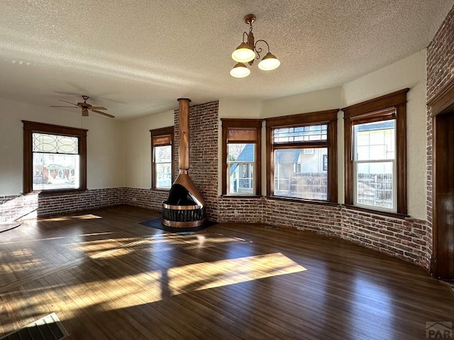 2023 N Elizabeth St, Pueblo, CO 81003 - unfurnished living room with wood finished floors, brick wall, a textured ceiling, healthy amount of natural light, and a chandelier
