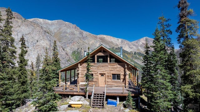 rear view of house with a deck with mountain view, stairs, and log siding