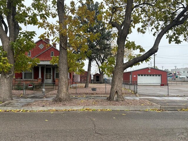 view of front facade featuring an outbuilding, a fenced front yard, and a garage