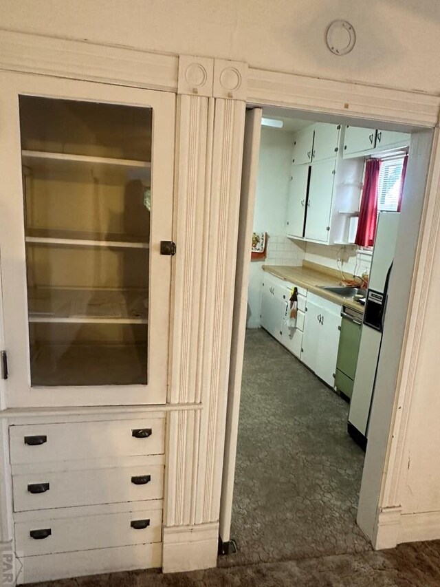 interior space featuring glass insert cabinets, white cabinetry, a sink, and dishwashing machine