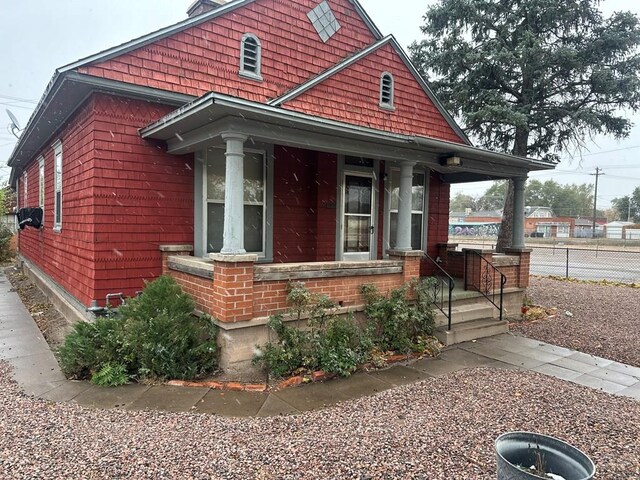 view of front facade featuring fence, a porch, and brick siding