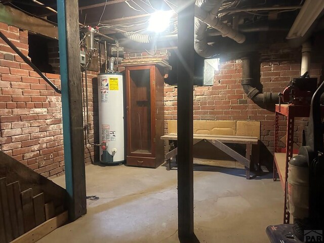 unfinished below grade area featuring water heater and brick wall