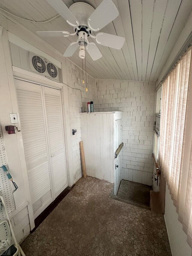 washroom featuring a ceiling fan, wooden ceiling, and brick wall