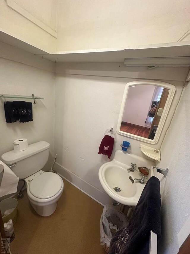 bathroom featuring toilet, baseboards, and a sink