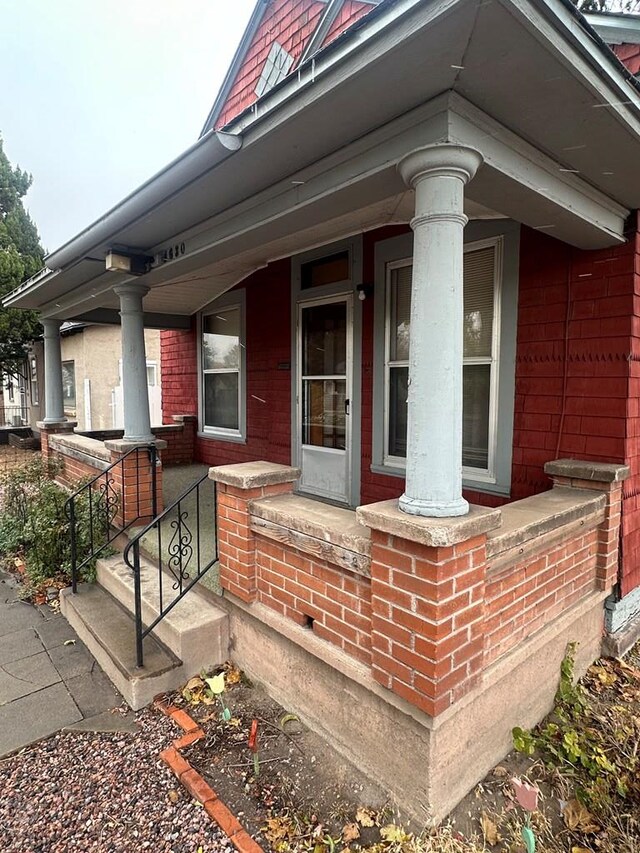 view of exterior entry with covered porch and brick siding