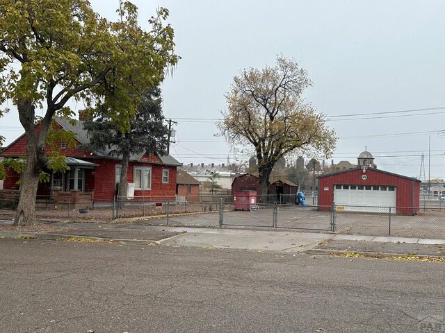 view of front of property featuring an outbuilding, a detached garage, and fence