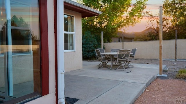 patio terrace at dusk with outdoor dining area and fence