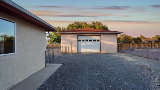 detached garage featuring driveway and fence