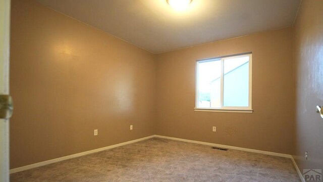 carpeted empty room featuring visible vents and baseboards