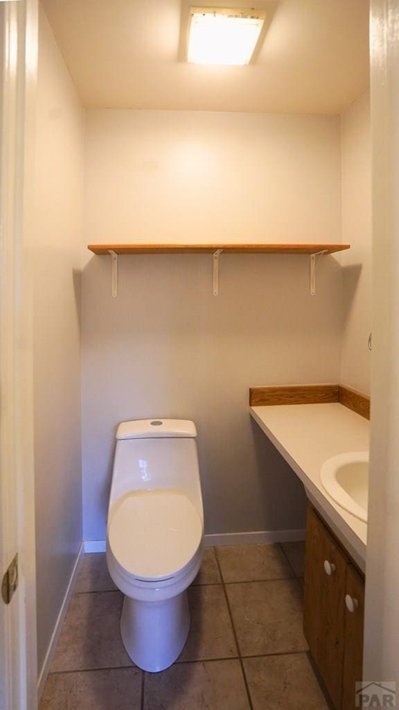 bathroom with tile patterned flooring, toilet, vanity, and baseboards