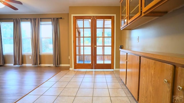 doorway featuring a ceiling fan, french doors, baseboards, and light tile patterned floors