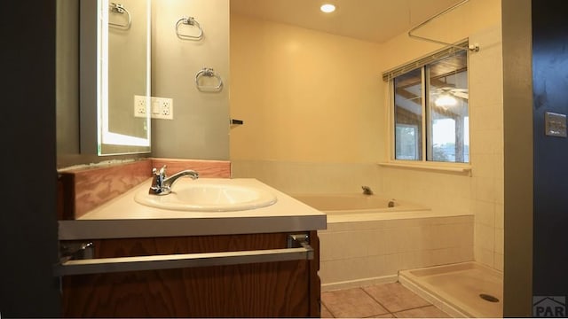 bathroom with tiled tub, tile patterned flooring, and vanity