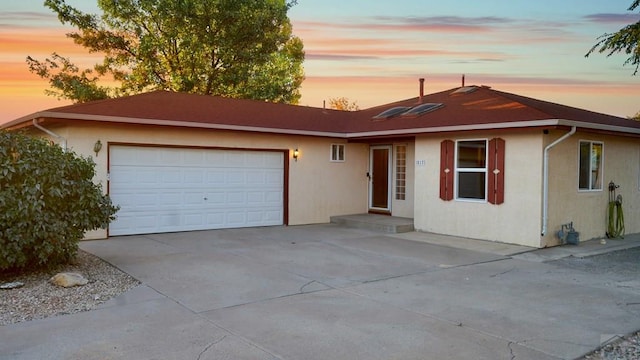 ranch-style home featuring driveway, an attached garage, and stucco siding