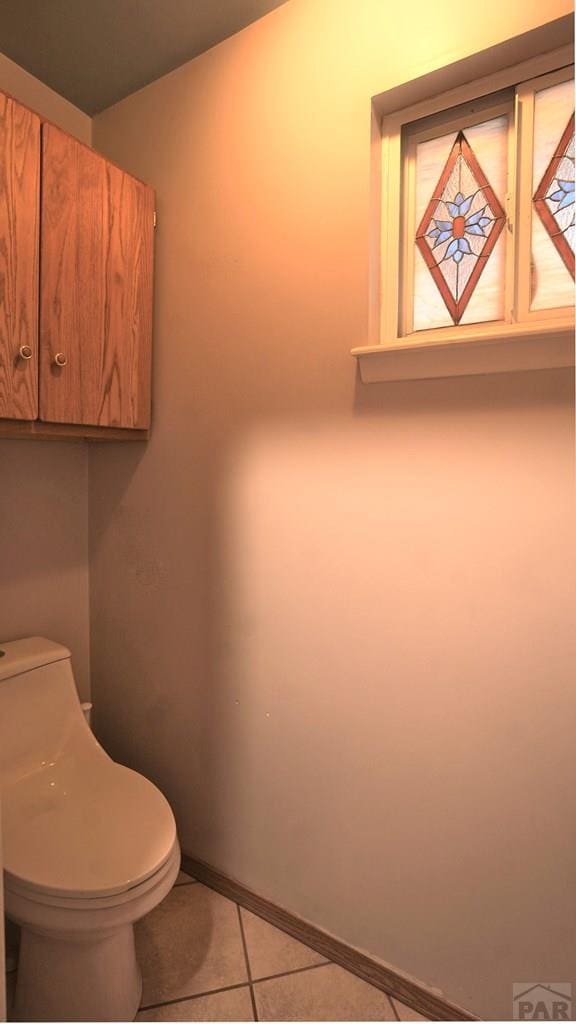 bathroom featuring tile patterned flooring, toilet, and baseboards