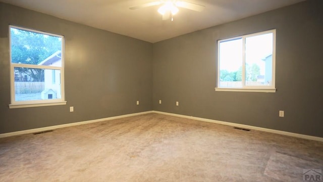 carpeted empty room featuring a ceiling fan, visible vents, and baseboards