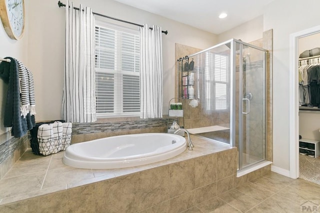 full bathroom featuring a shower stall, a healthy amount of sunlight, a spacious closet, and a garden tub