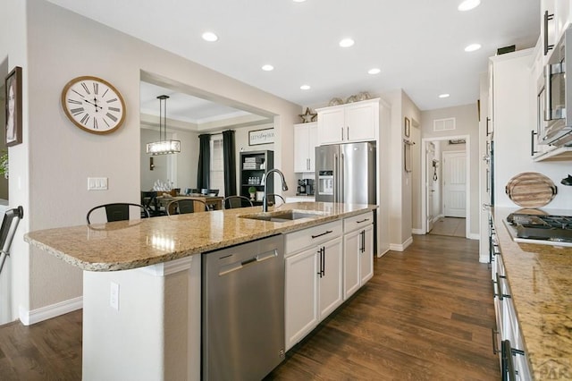 kitchen with white cabinets, a sink, appliances with stainless steel finishes, and dark wood finished floors