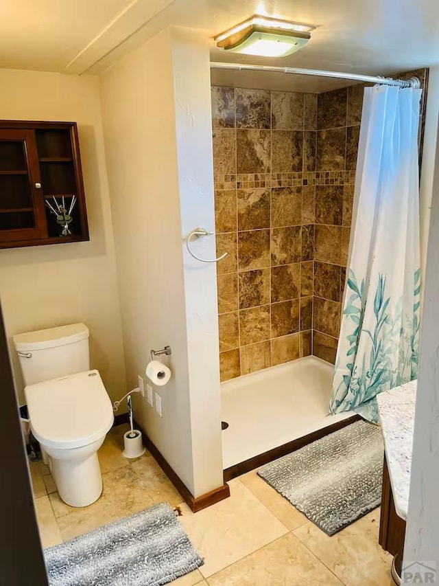 full bath with toilet, a shower stall, baseboards, and tile patterned flooring