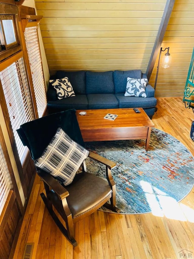 living area featuring wood walls, visible vents, and wood finished floors