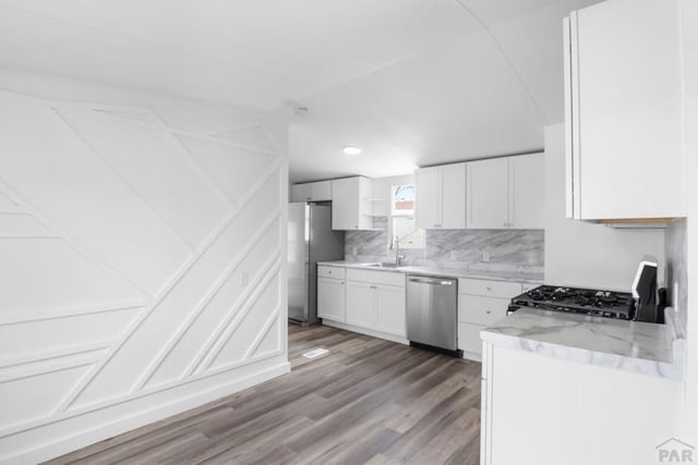 400 Hickory St Unit 172, Fort Collins, CO 80524 - kitchen with a sink, decorative backsplash, wood finished floors, white cabinets, and appliances with stainless steel finishes