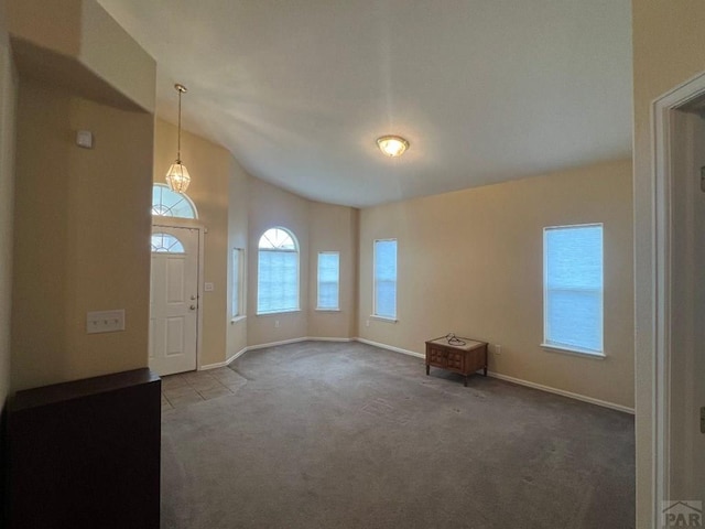 carpeted foyer entrance with vaulted ceiling and baseboards