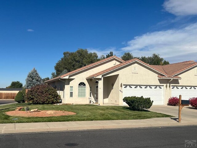 view of front of home featuring a garage, driveway, a tile roof, and stucco siding