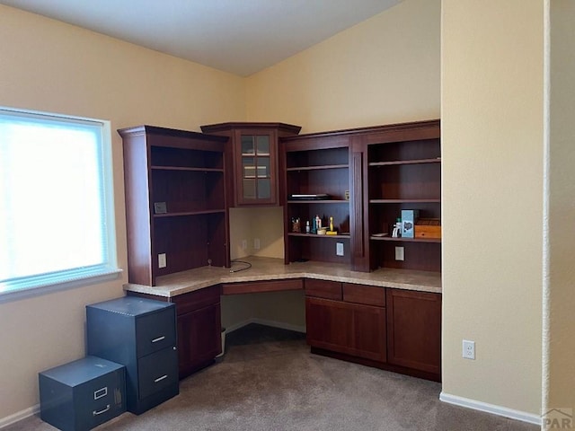 unfurnished office featuring baseboards, built in study area, and light colored carpet