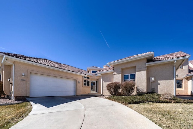 view of front of property featuring stucco siding, a tile roof, and a garage