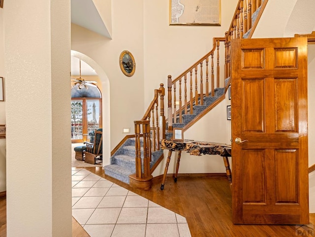 interior space with arched walkways, a high ceiling, baseboards, and wood finished floors