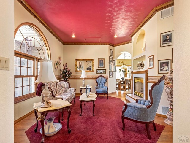 living room with ornamental molding, a fireplace, wood finished floors, and visible vents