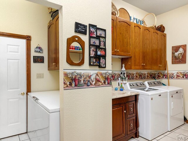 laundry area featuring cabinet space, washing machine and clothes dryer, and light tile patterned floors