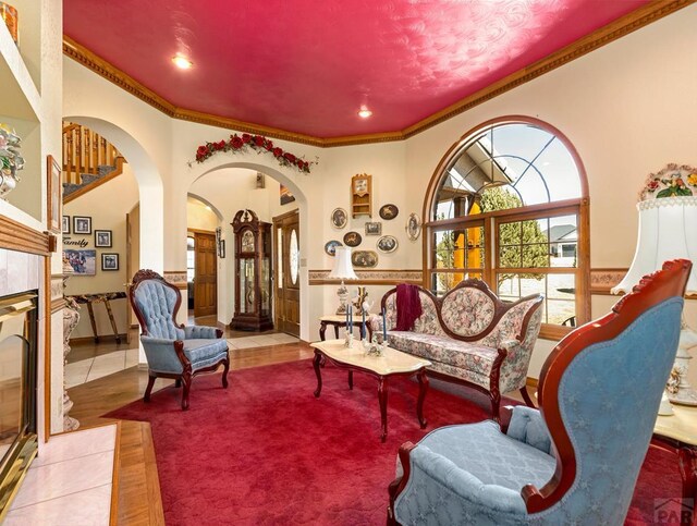 living area featuring tile patterned flooring, arched walkways, and crown molding