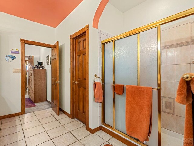 bathroom with baseboards, tile patterned flooring, and a shower stall