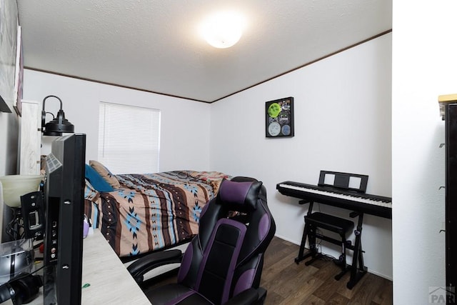 bedroom with ornamental molding, dark wood-style flooring, and a textured ceiling