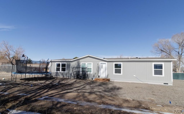 rear view of property with crawl space, a trampoline, and entry steps