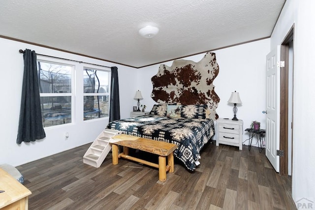 bedroom featuring ornamental molding, dark wood-type flooring, and a textured ceiling