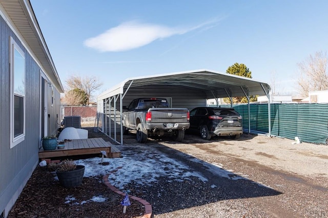 view of parking / parking lot with a detached carport, fence, and dirt driveway