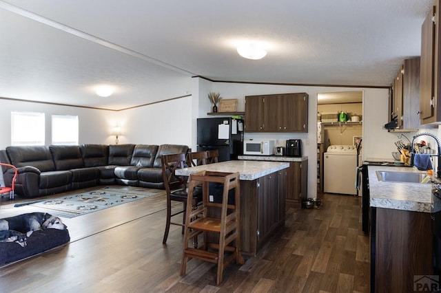 kitchen featuring a kitchen island, open floor plan, light countertops, freestanding refrigerator, and washer / clothes dryer