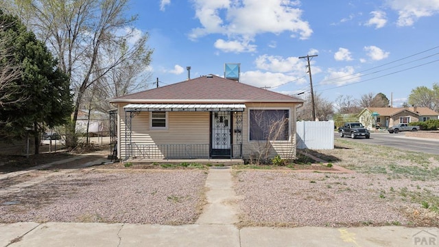 bungalow featuring roof with shingles and fence